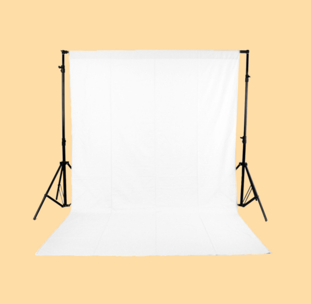 photograph of a white fabric studio backdrop on two stands against a warm yellow background
