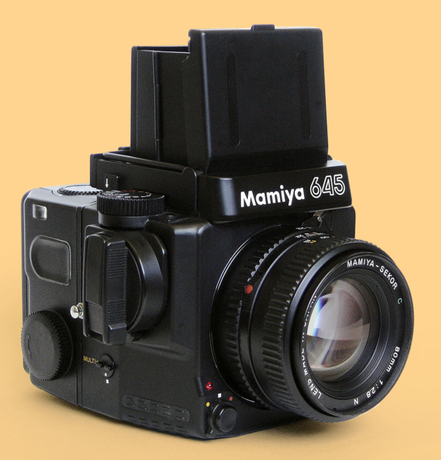 Photograph of a medium format Mamiya camera against a warm yellow background