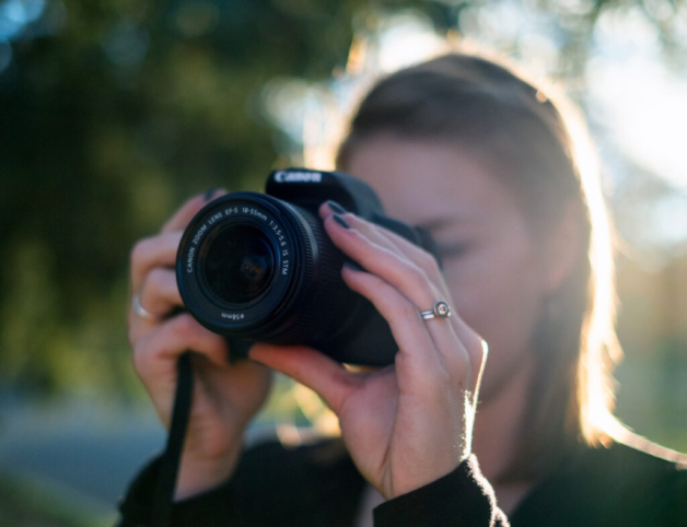 An image of a woman holding a camera up to her face, ready to take an image