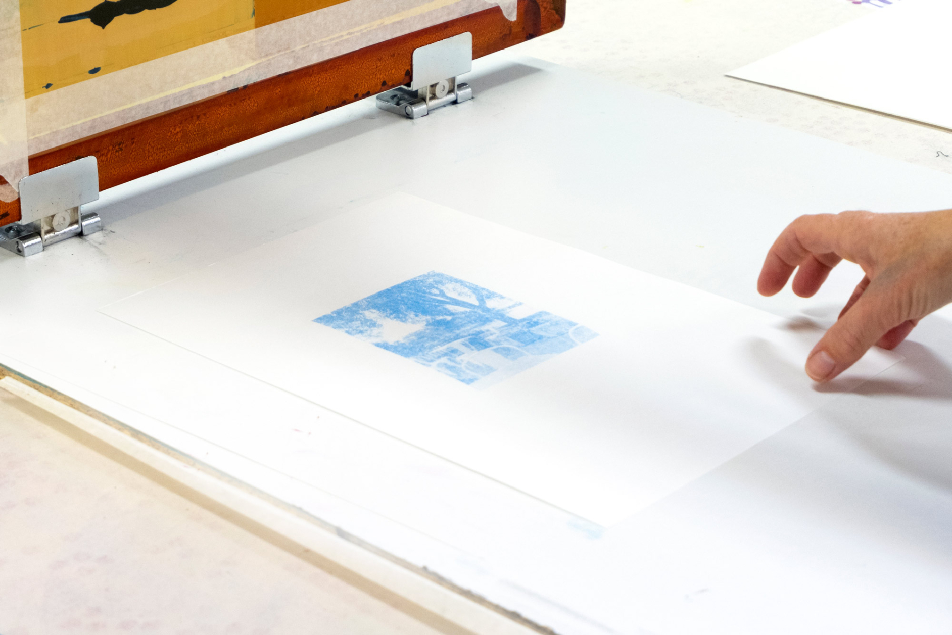 A blue image printed on a white sheet of paper, hand to the right side of the frame