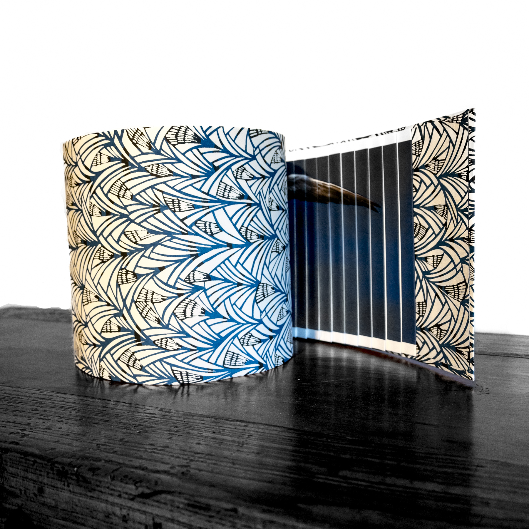 A photograph of a circular book slightly open, with a geometric print