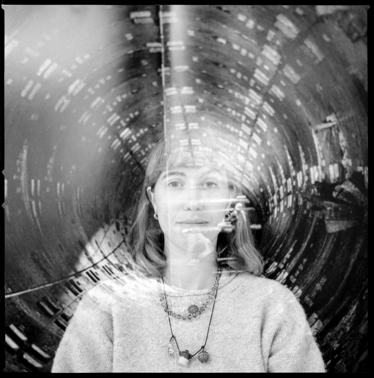 A black and white image of a girl with short hair, overlapped with a double exposure image
