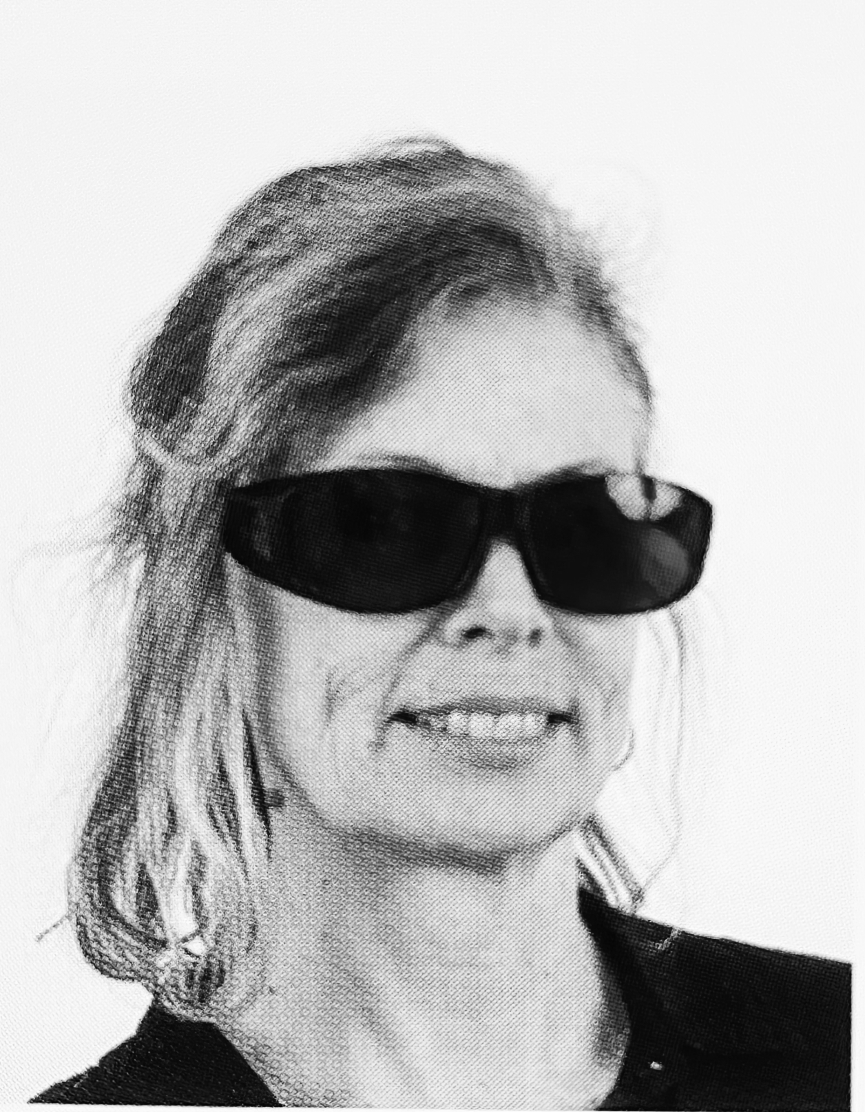 A black and white photograph of a woman smiling wearing large dark sunglasses